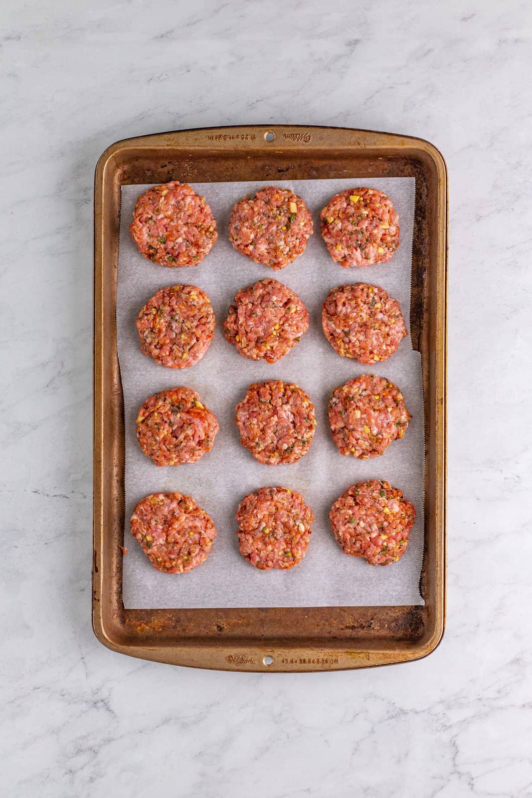 Sausage patties on parchment lined baking sheet.
