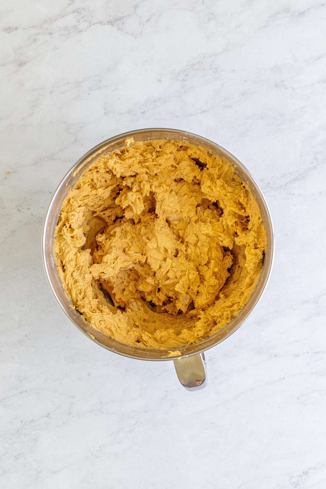 Cookie dough mixed together in bowl of stand mixer.