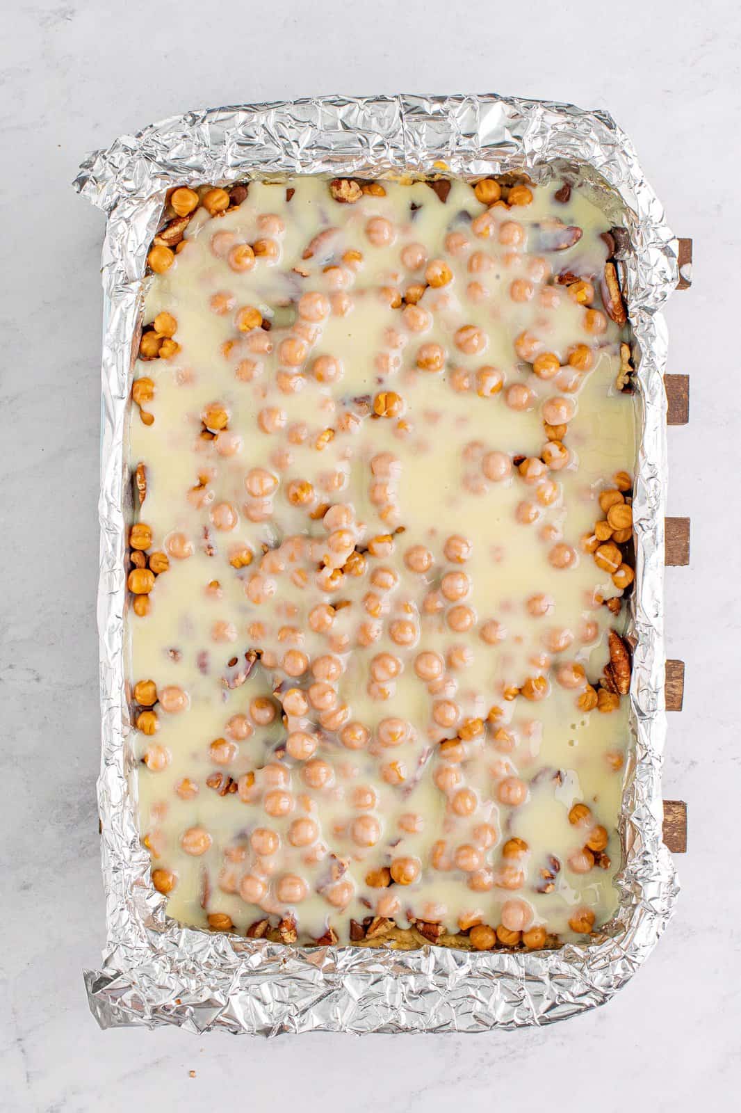 Sweetened condensed milk poured over the top of the chocolate chips, pecans and caramel bits.