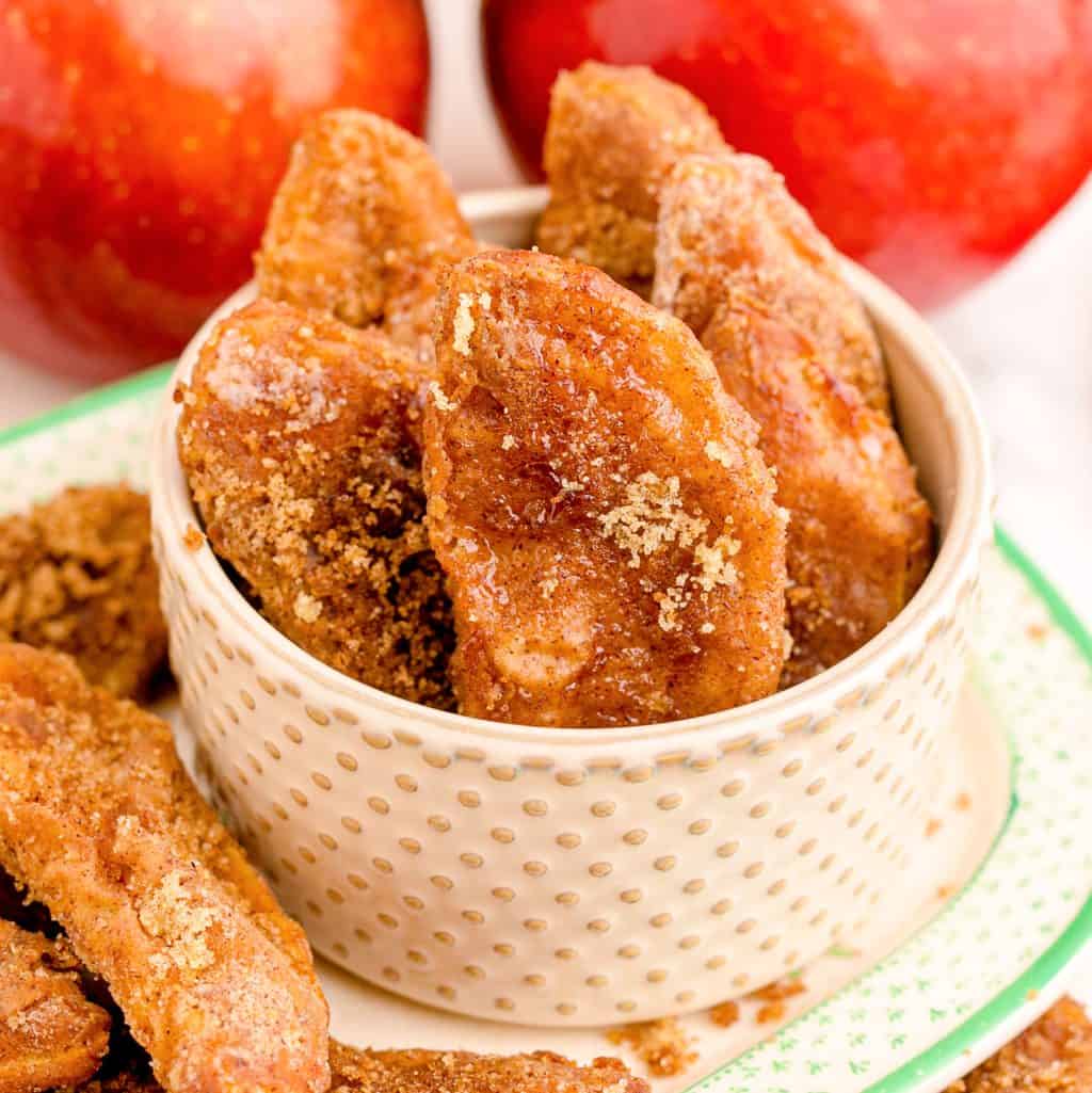 Close up square image of Air Fryer Apple Fries in white bowl on platter.