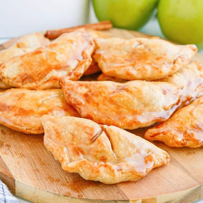 Close up of finished glazed Air Fryer Apple Hand Pies on wooden board.