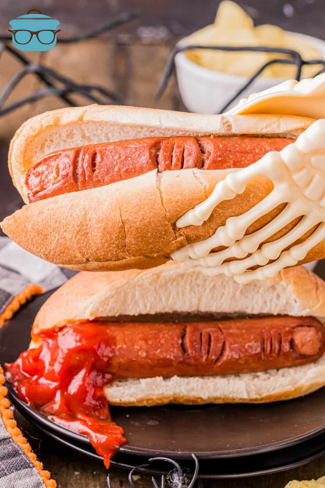 Halloween Hot Dog Fingers in buns with a skeleton hand holding one up.