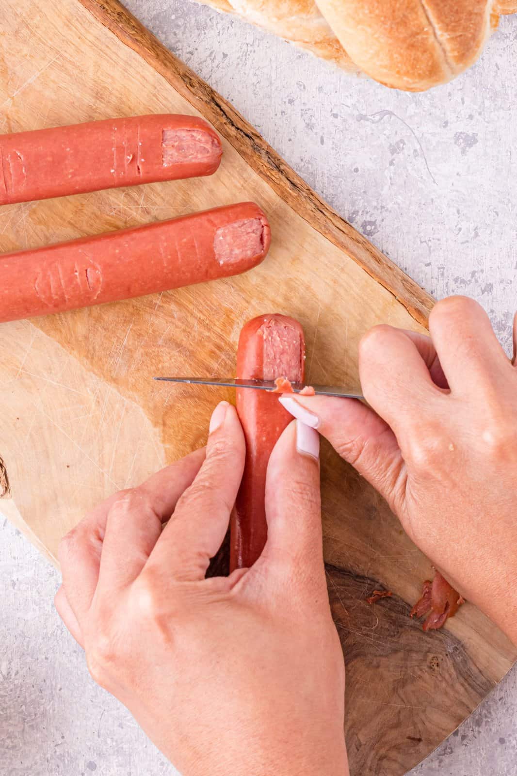 Knife scraping off a portion of the hot dog to make the fingernail.