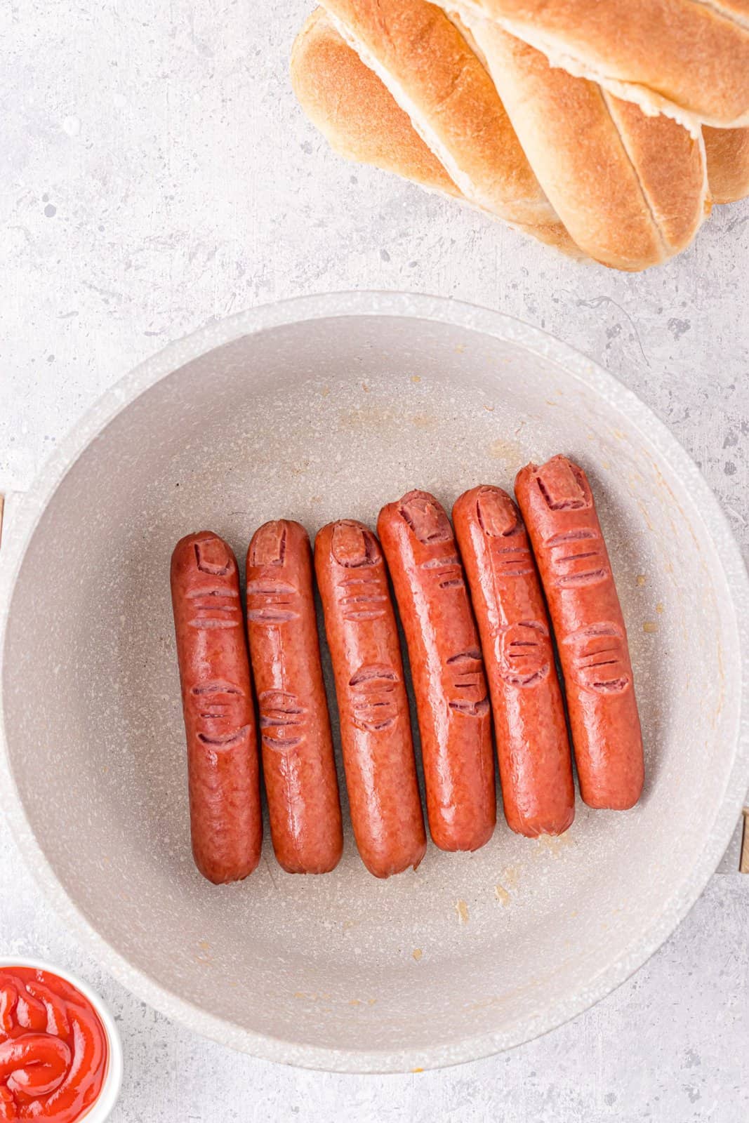 Hot dogs being fried in pan.