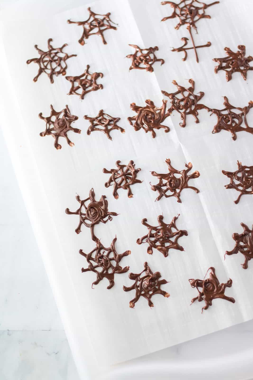 Chocolate spiderwebs piped onto parchment paper.