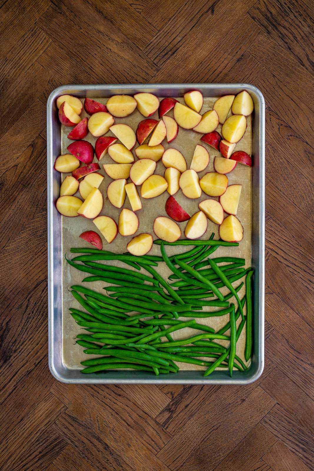 Potatoes and green beans placed on sheet pan.