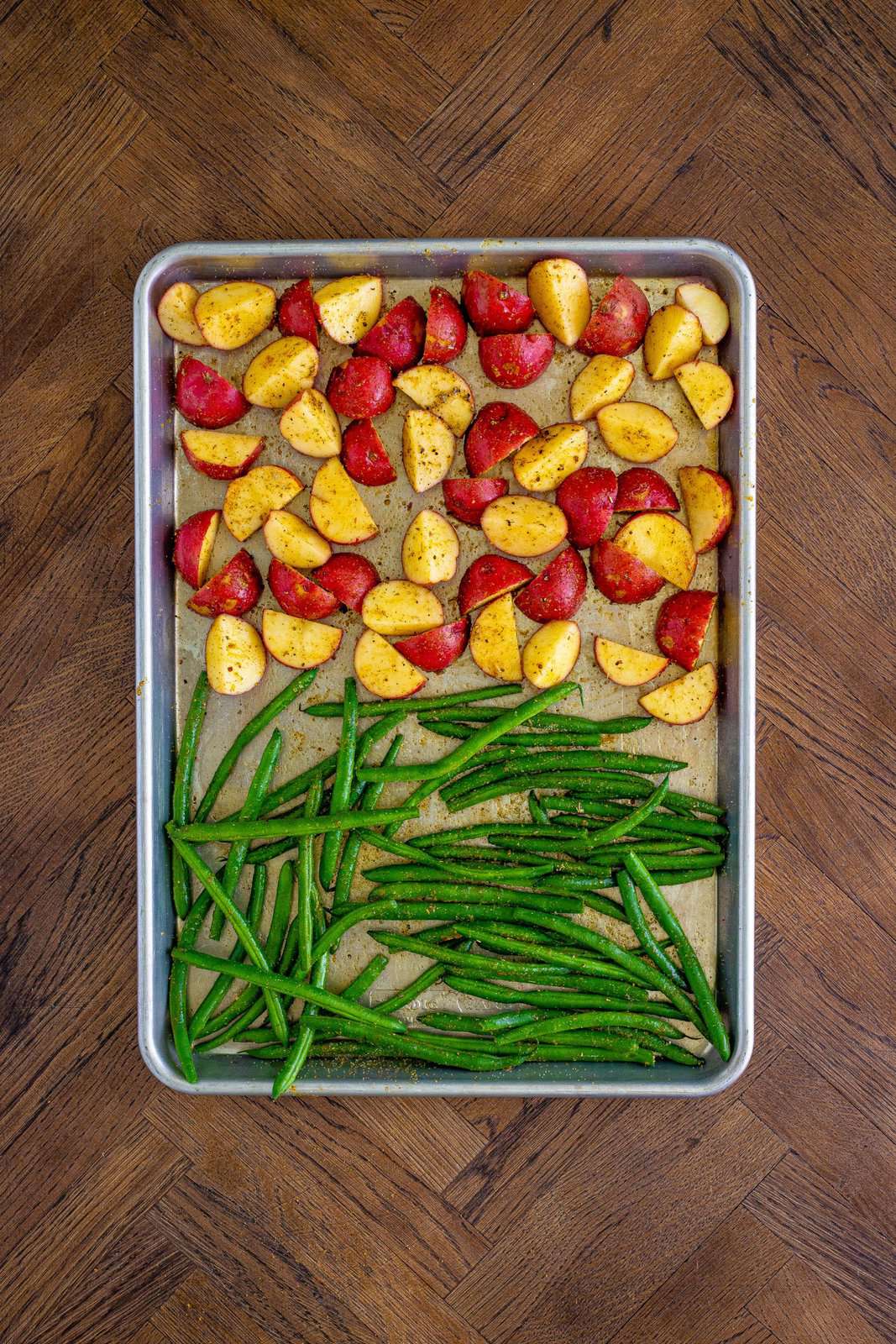 Seasoning mixture rubbed all over potatoes and green beans on sheet pan.