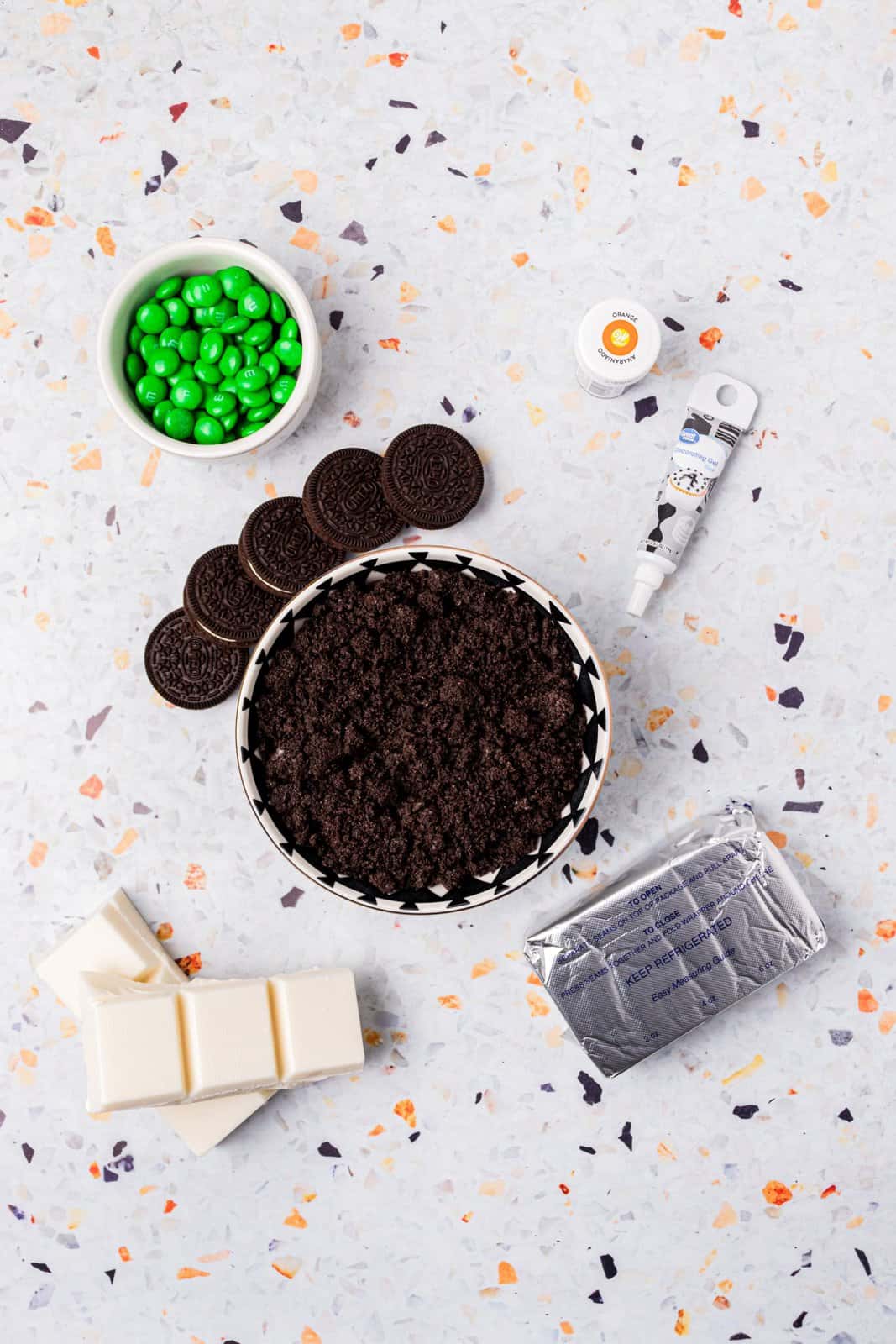 Ingredients needed: Double Stuf Oreos, cream cheese, white almond bark, orange food coloring, green M&M’s and black gel icing.