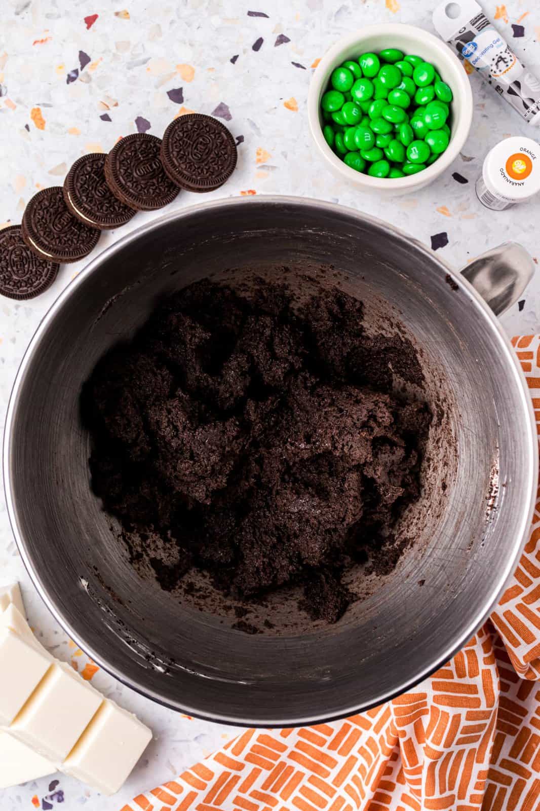 Cream cheese and Oreo crumbs mixed together in bowl of stand mixer.