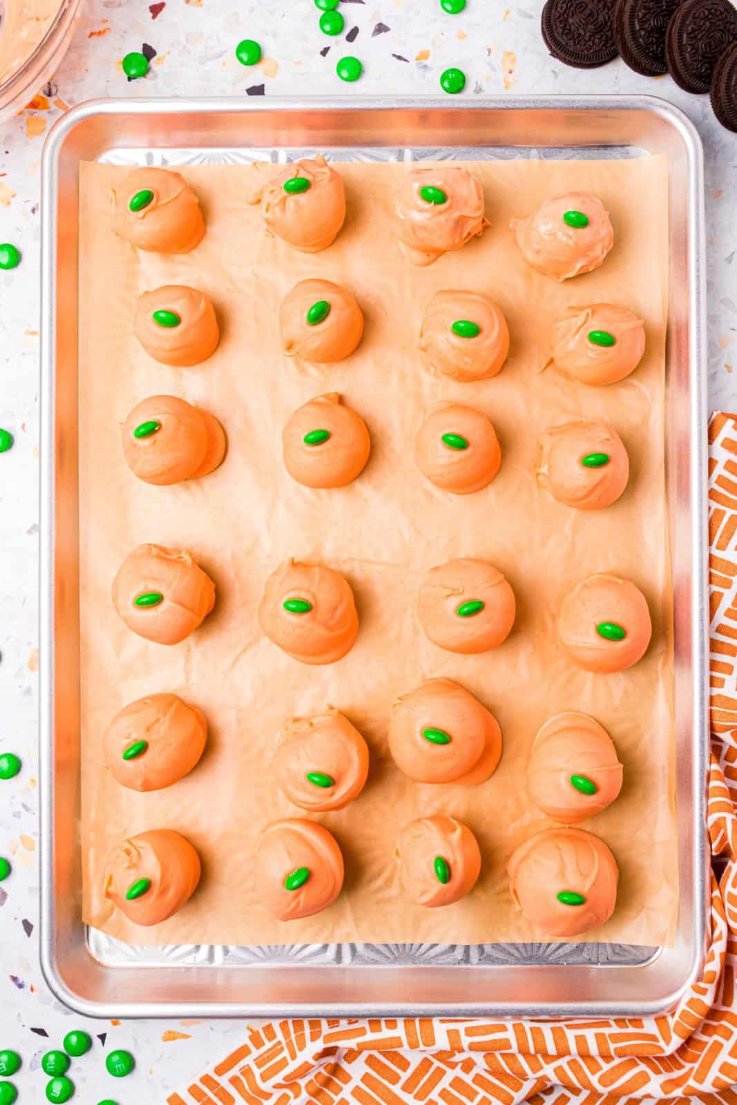 Balls placed back on parchment lined baking sheet topped with green M&M's.