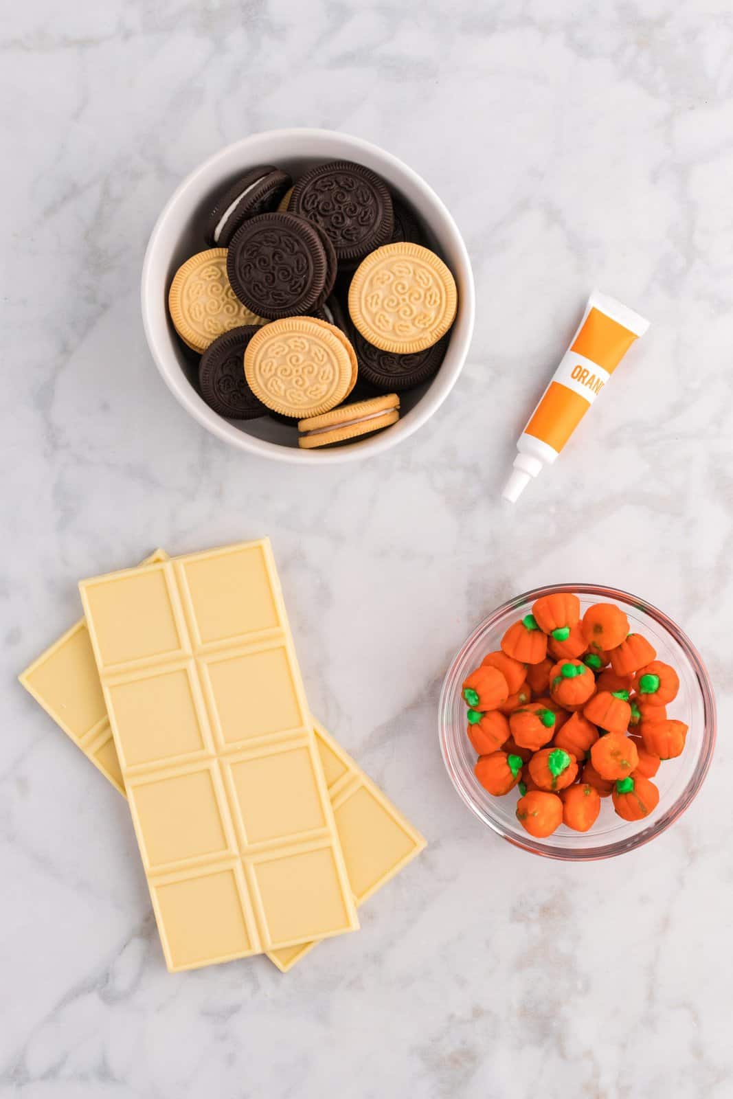 Ingredients needed: vanilla and chocolate sandwich creme cookies, white melting chocolate, orange gel food coloring and mellowcreme pumpkin candies.