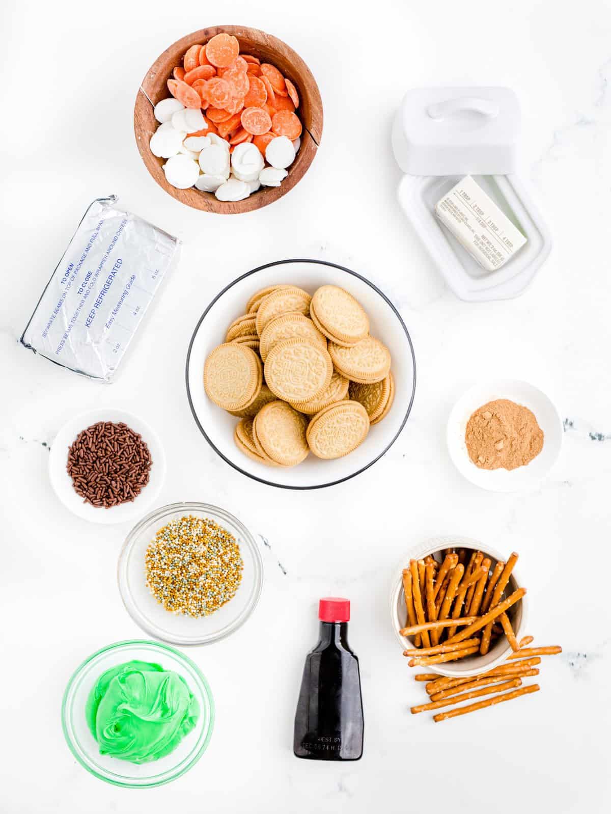 Ingredients needed: Golden Oreo Cookies, cream cheese, butter, vanilla extract, pumpkin spice, colored candy melts, green icing, pretzel sticks and Fall colored sprinkles.