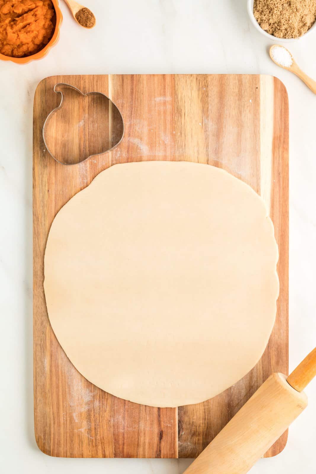 One pie crust rolled out on cutting board.
