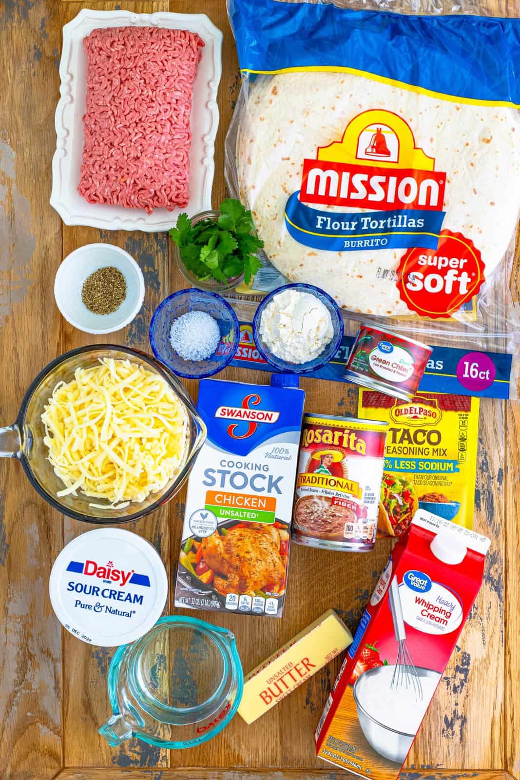 Ingredients needed: lean ground beef, taco seasoning, water, refried beans, Monterey Jack cheese, unsalted butter, all-purpose flour, unsalted chicken stock, heavy cream, diced green chiles, sour cream, kosher salt, pepper, burrito-sized tortillas and fresh chopped cilantro.