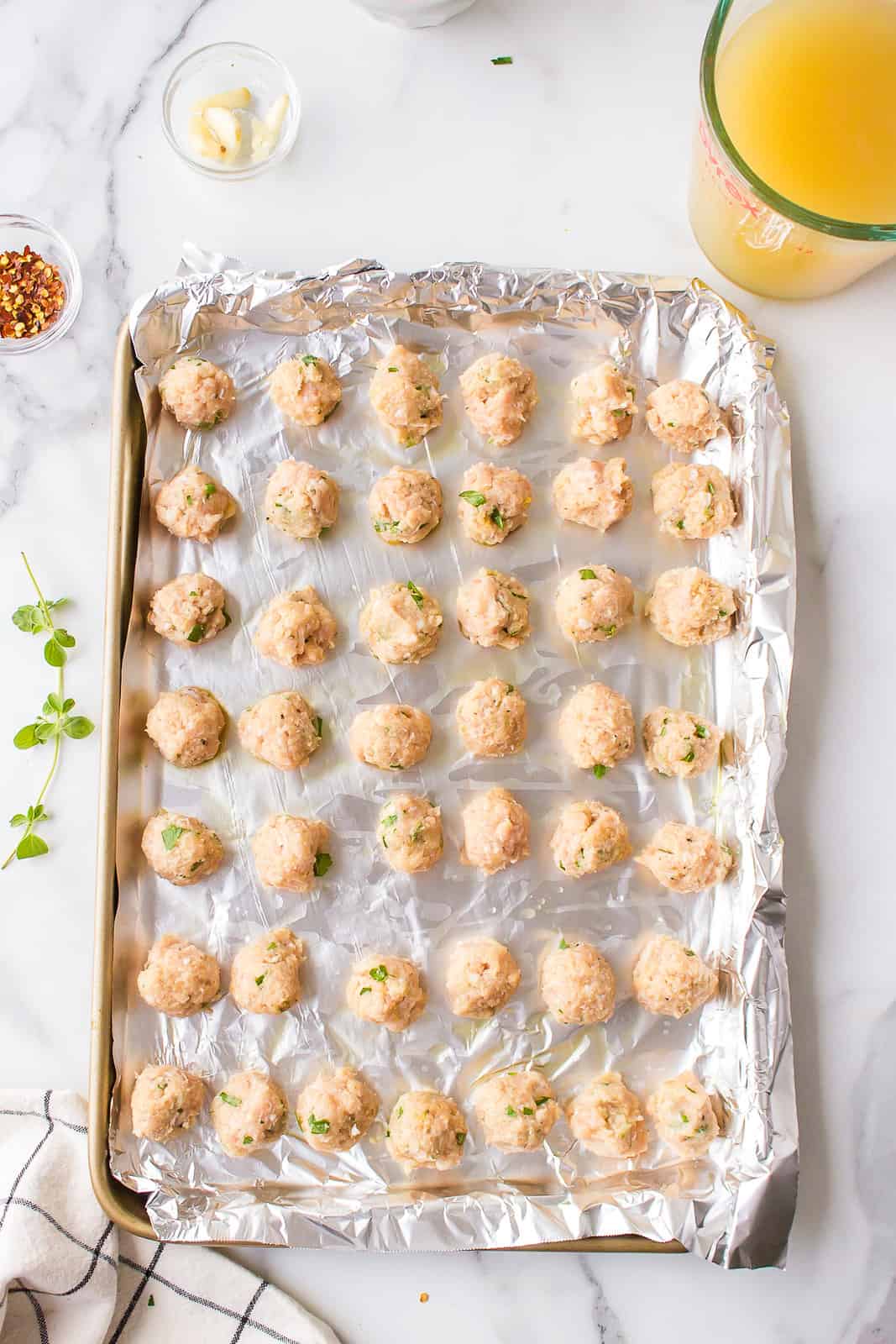 Meat mixture shaped into meatballs and placed on a foil lined baking sheet.