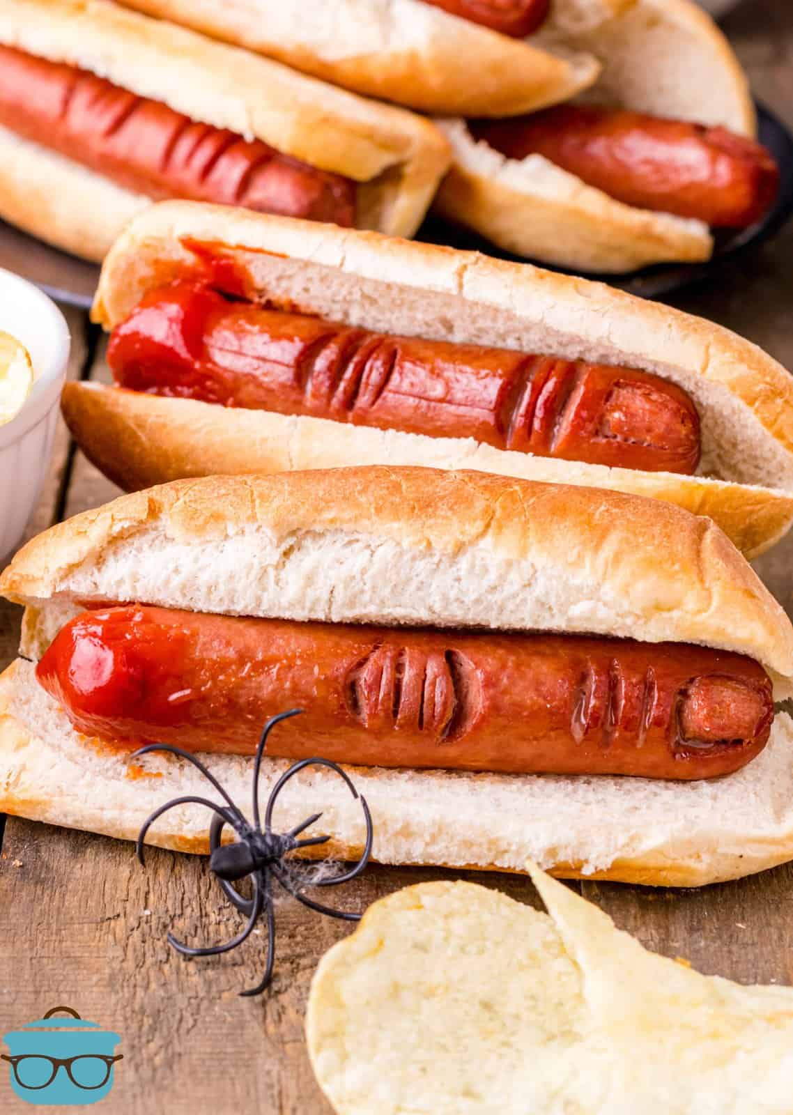 Halloween Hot Dog Fingers in buns with chips and a fake spider.
