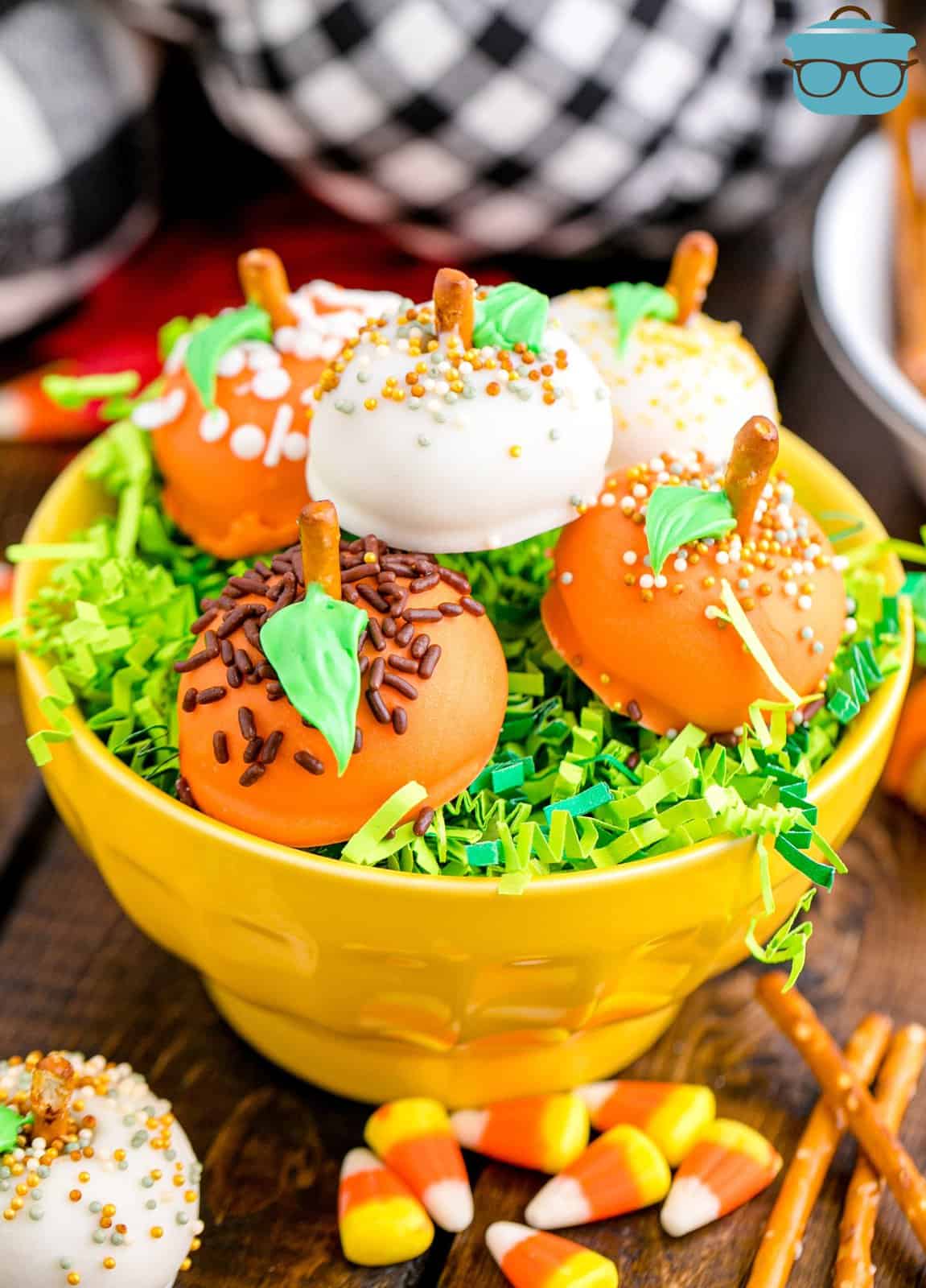 Yellow bowl with fake green grass with stacked Pumpkin Oreo Balls.