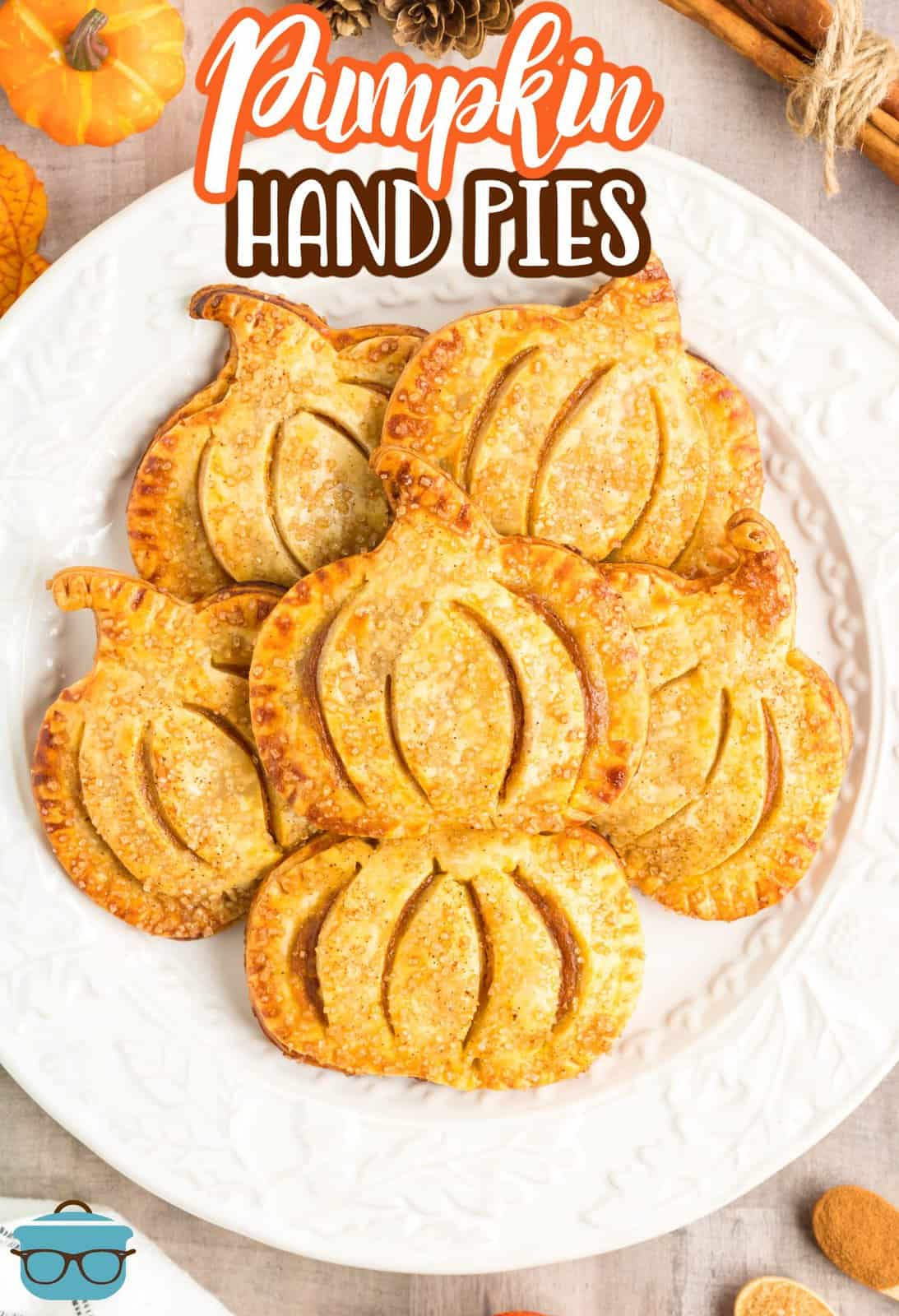 Immagine Pinterest sopra la testa di Pumpkin Hand Pies impilati su un piatto bianco.