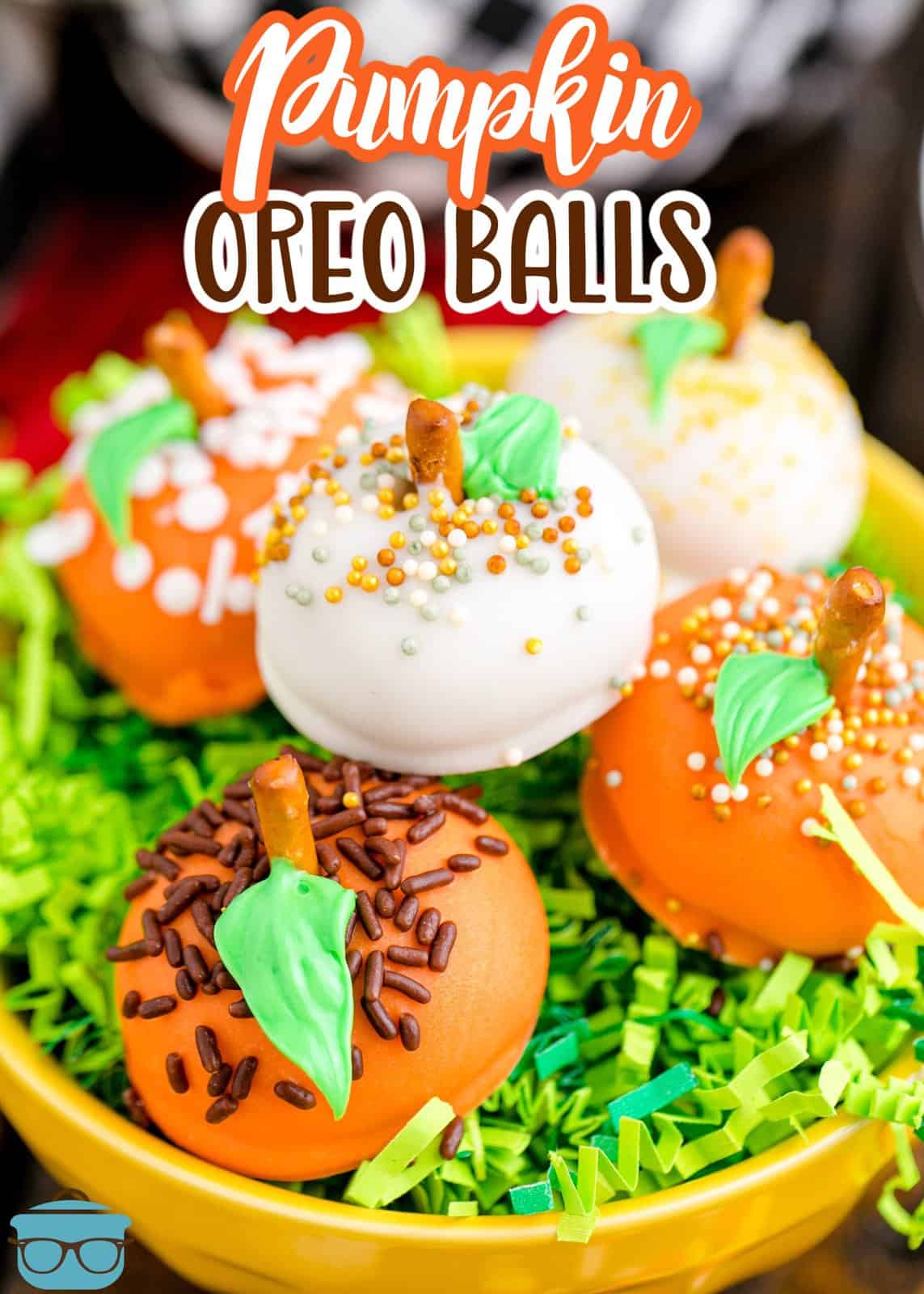 Pinterest image of stacked Pumpkin Oreo Balls in yellow bowl with fake green grass, decorated.