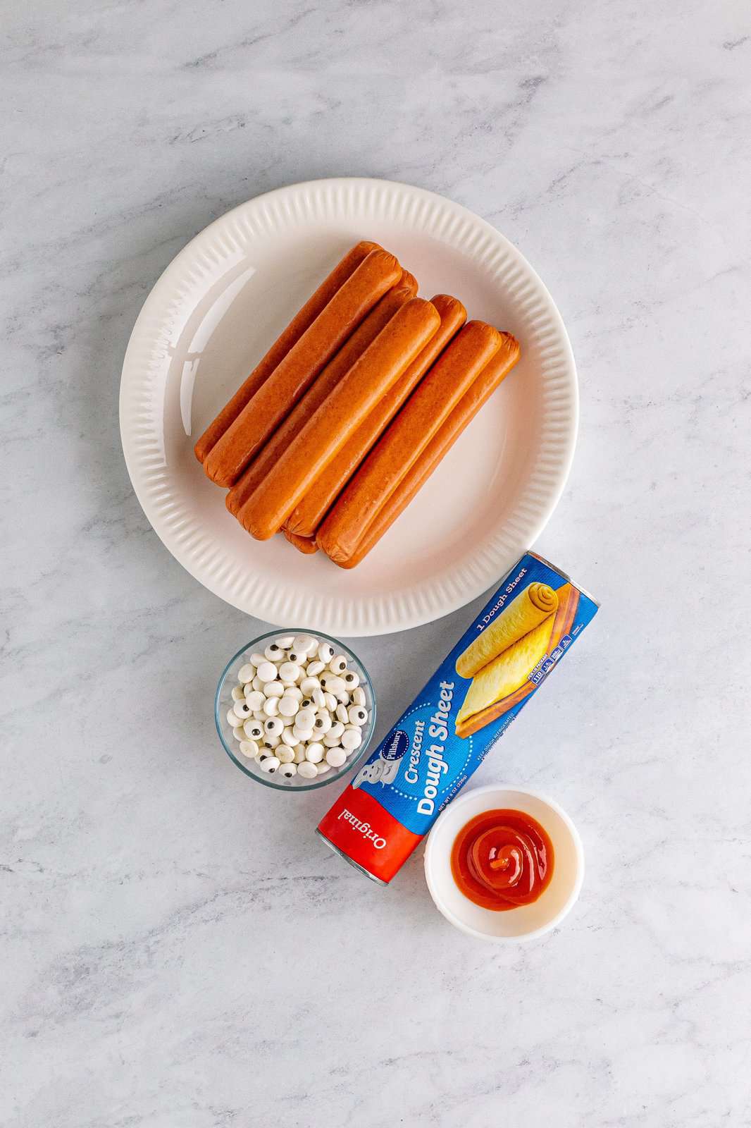 Ingredients needed: hot dogs, sheet crescent roll dough, ketchup, candy eyes and your favorite sauces for dipping.