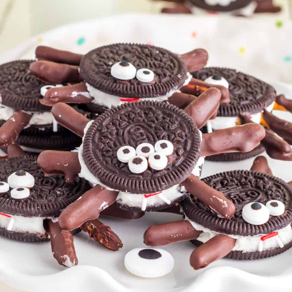 Square image of stacked Halloween Oreo Spiders on white plate.