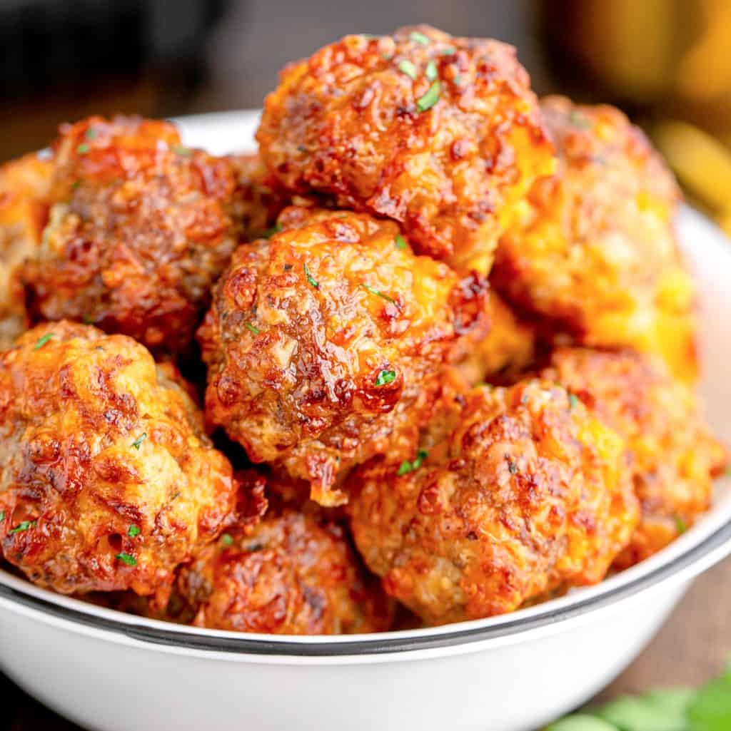 Close up of finished Air Fryer Sausage Balls stacked up in bowl.