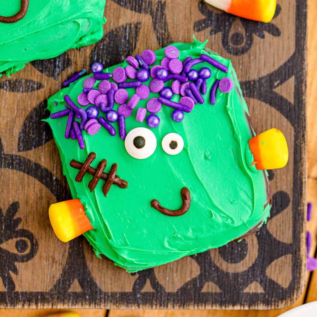 Close up square image of one of the finished decorated Easy Frankenstein Cookies on wooden and black board.