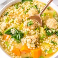 Square close up of Italian Wedding Soup in bowl with gold spoon.