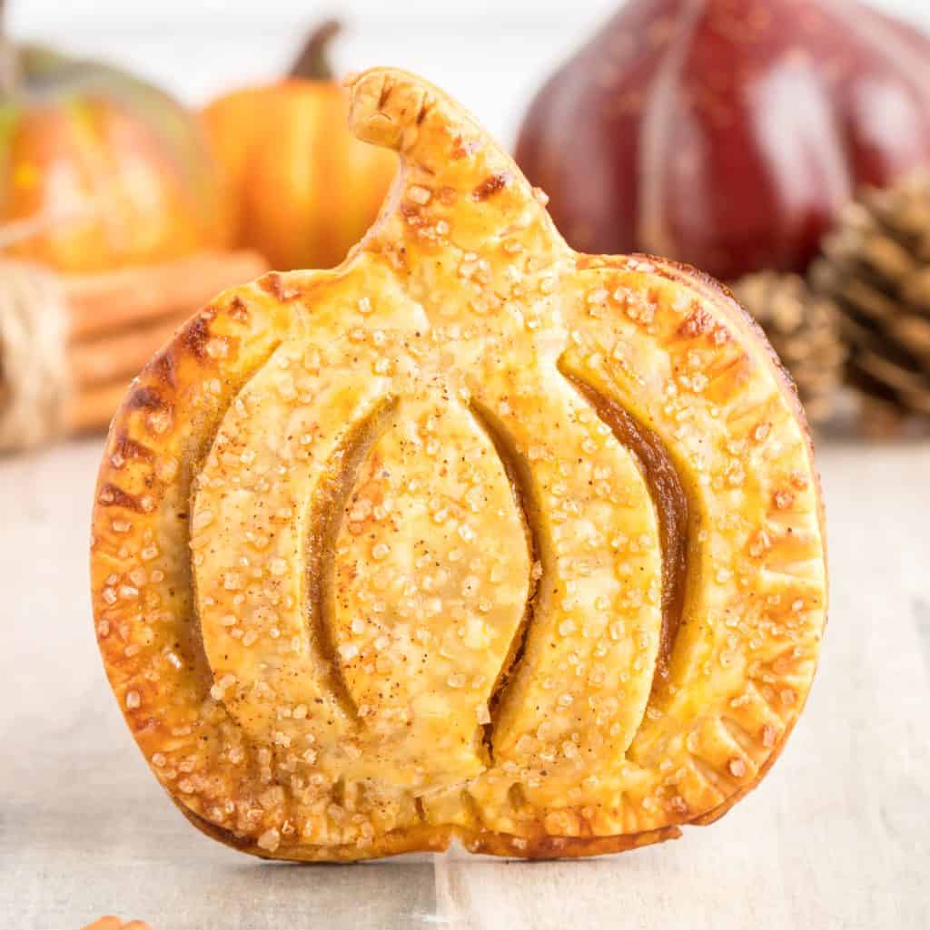 Close up square image of one of the Pumpkin Hand Pies propped up showing pumpkin shape.