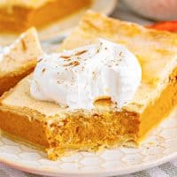 Close up square image of a slice of Pumpkin Slab Pie with bite taken out of it, garnished.