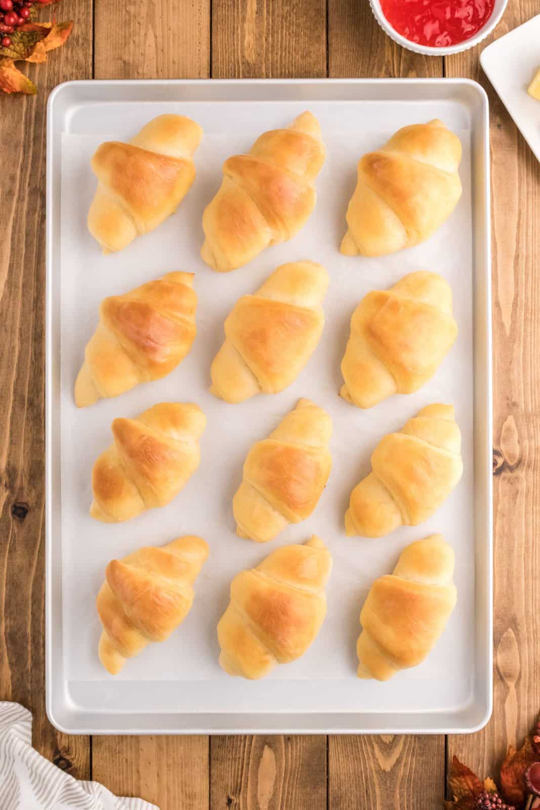 Finished Homemade Crescent Rolls on parchment lined baking sheet.