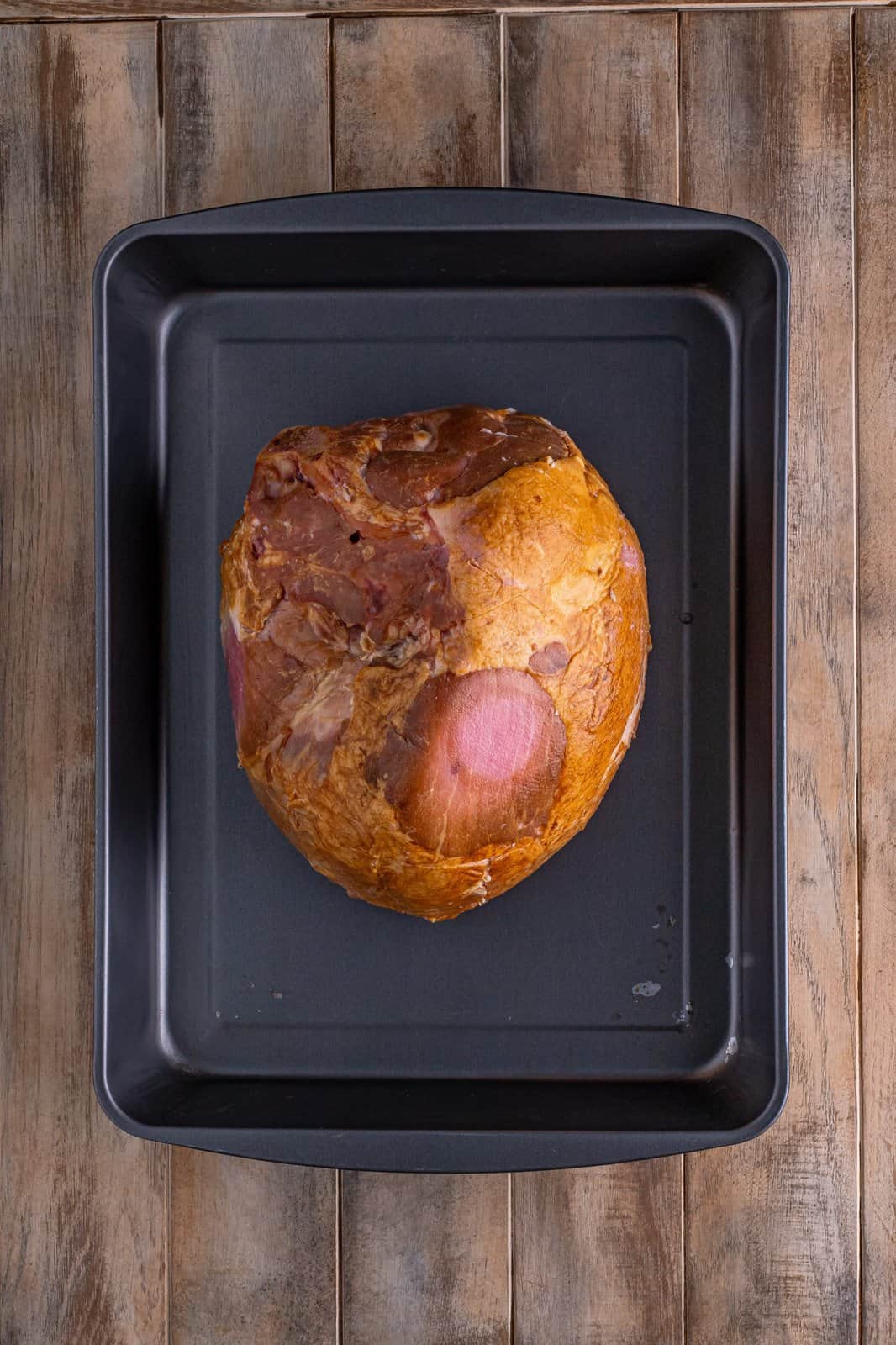 Ham placed on top of tin foil ring in baking pan.