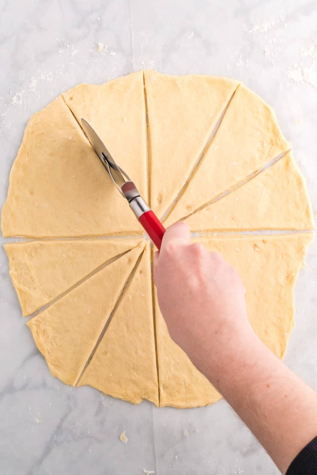 Dough being cut into 12 triangles.