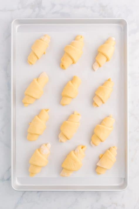Crescent roll dough placed on lined baking sheet.