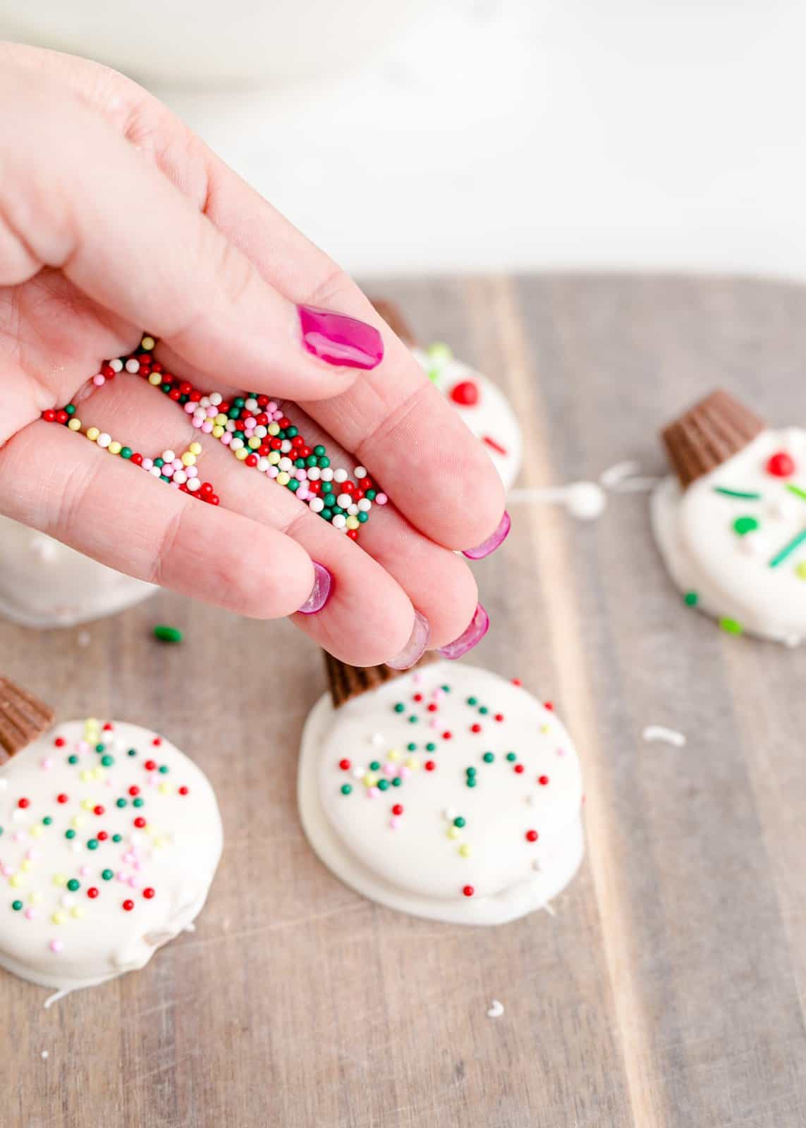 Sprinkles being added to the tops of the dipped crackers.