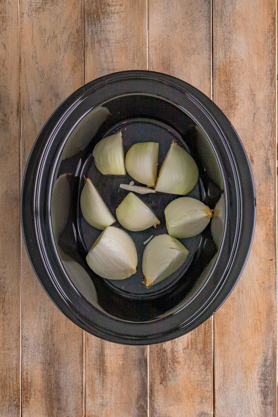 Onions placed in the bottom of a crock pot.