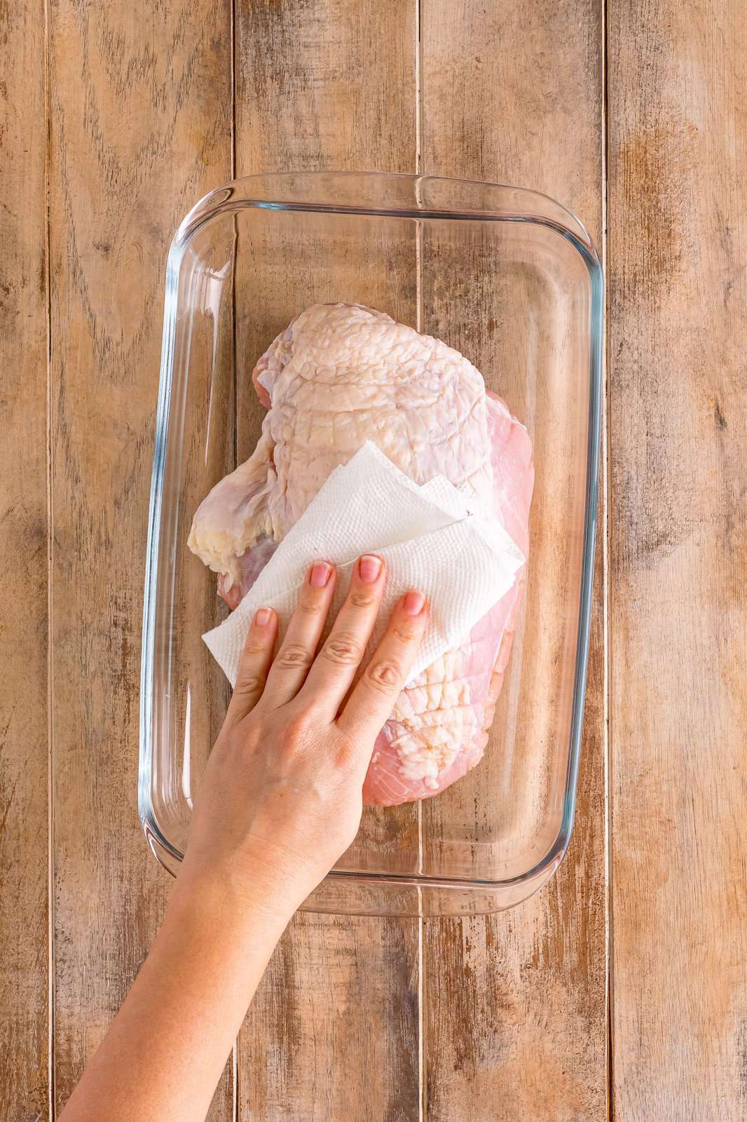 Paper towel patting turkey breast dry.