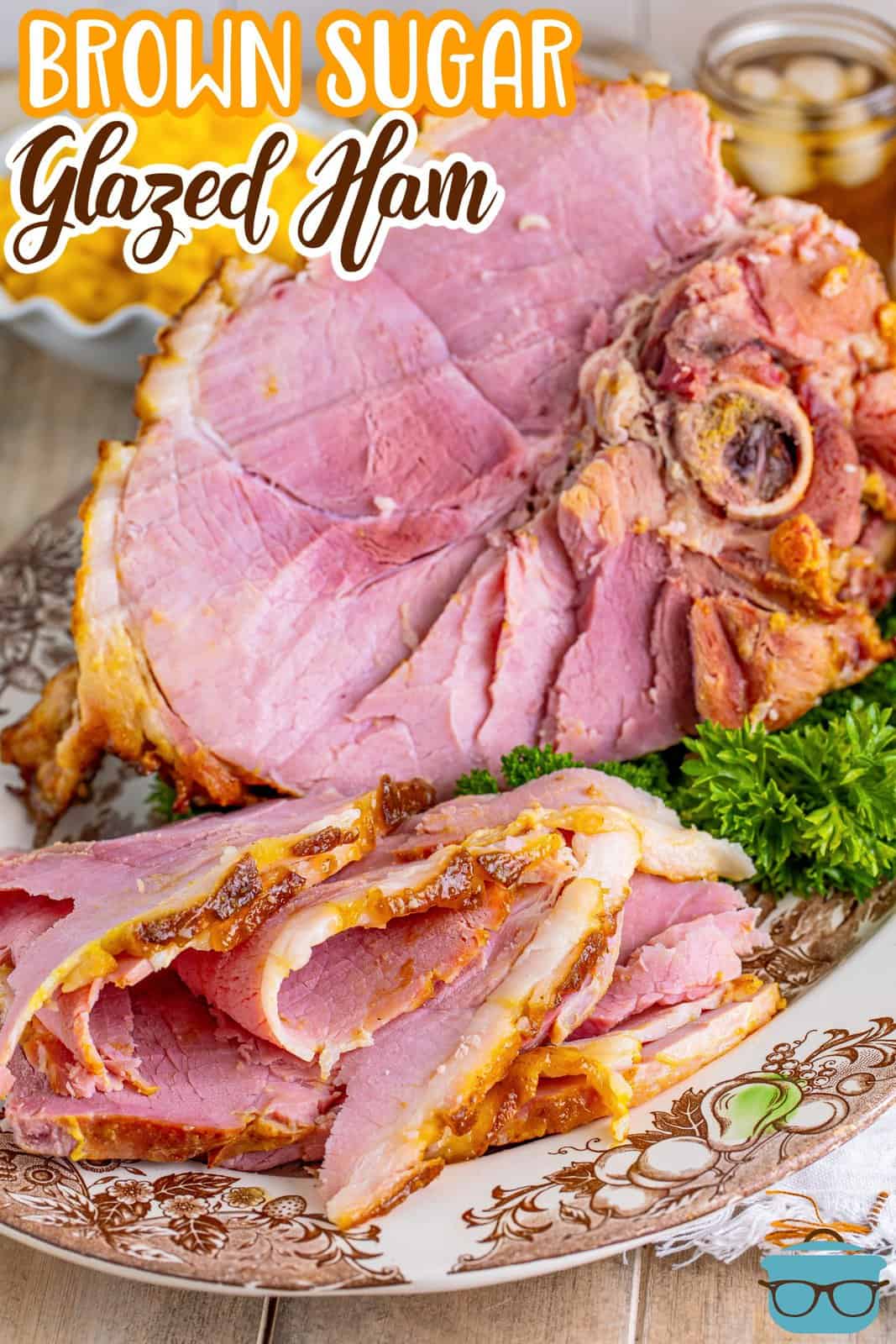 Pinterest image of carved Brown Sugar Glazed Ham on plate with whole ham on platter in back.