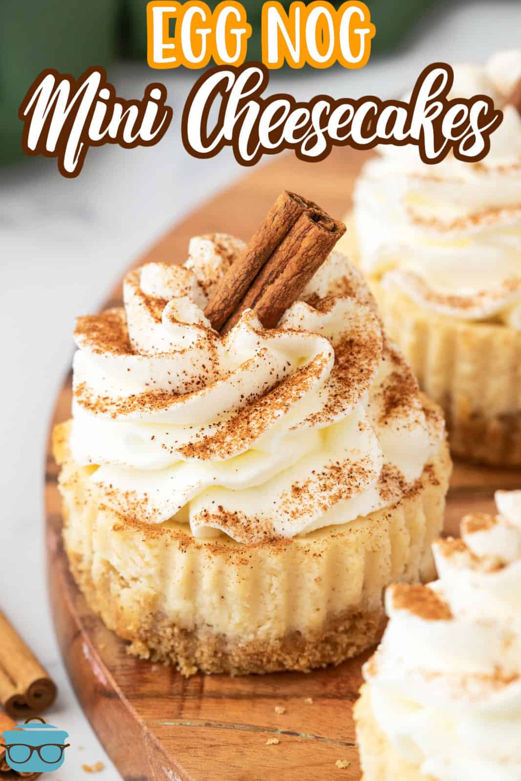 Pinterest image of Egg Nog Mini Cheesecakes on wooden board topped with garnishes.
