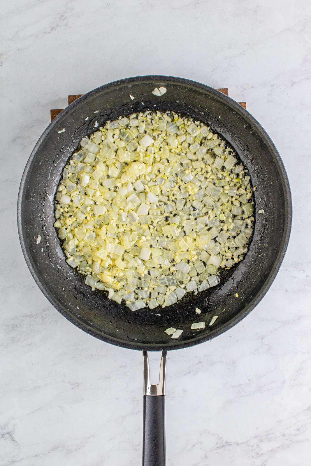 Burro, cipolle e aglio soffriggere in una padella.