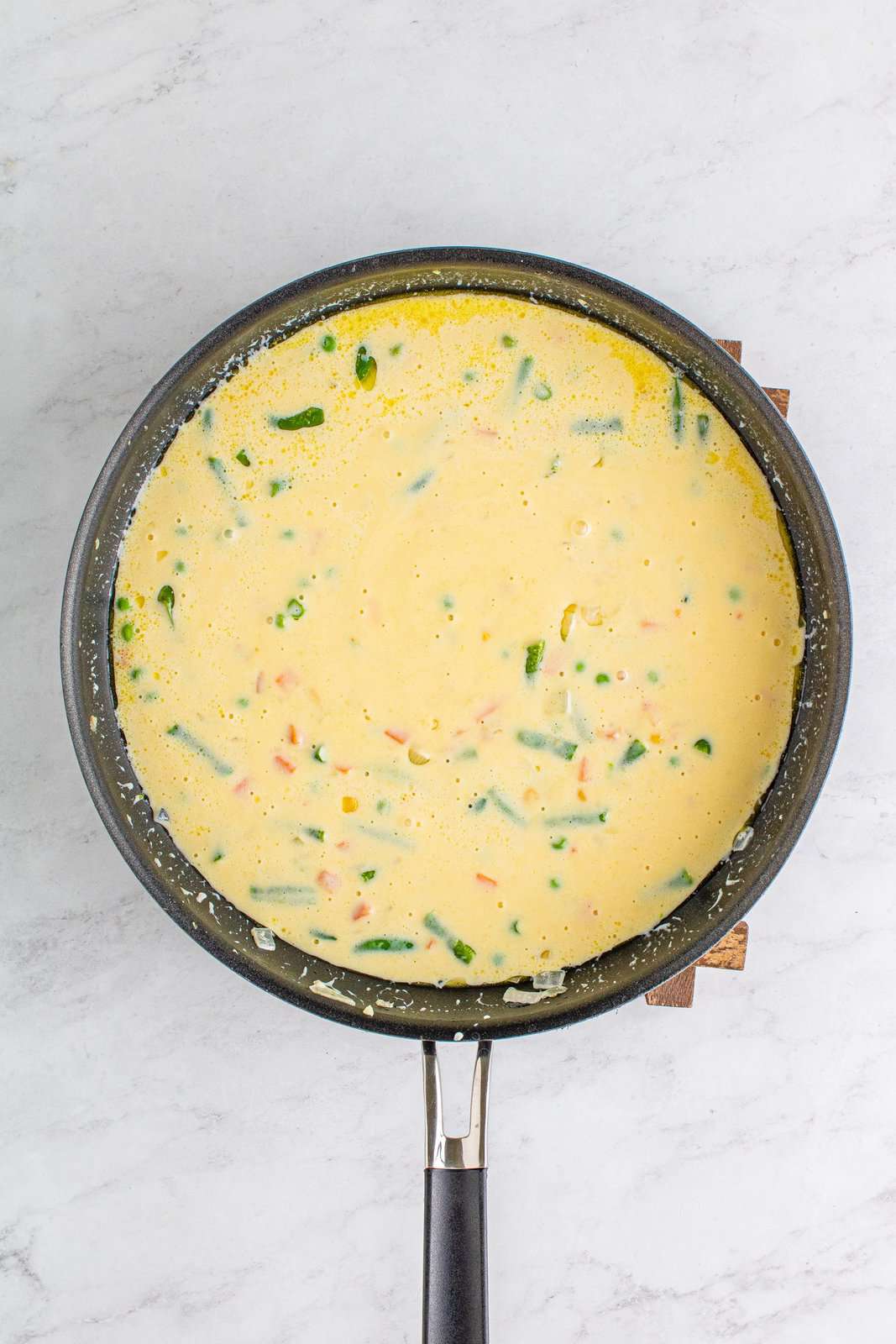 Metà e metà e crema di zuppa di pollo montate in una miscela di verdure in padella.