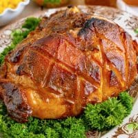 Close up square image of finished Brown sugar Glazed Ham on platter with parsley garnishes.
