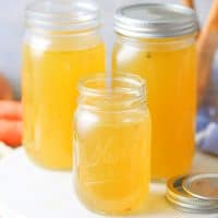 Close up square image of Homemade Chicken Stock in mason jars.