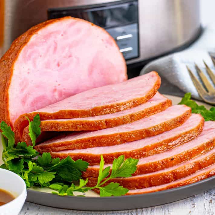 Close up square image of sliced Slow Cooker Boneless Ham on platter.