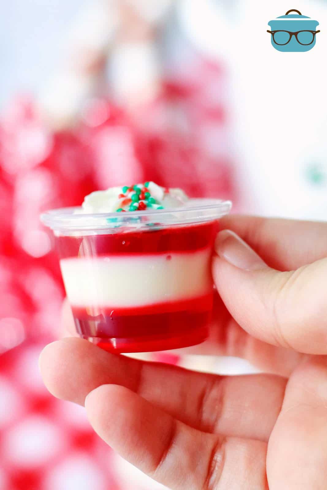 Hand holding up one of the Candy Cane Jell-O Shots.