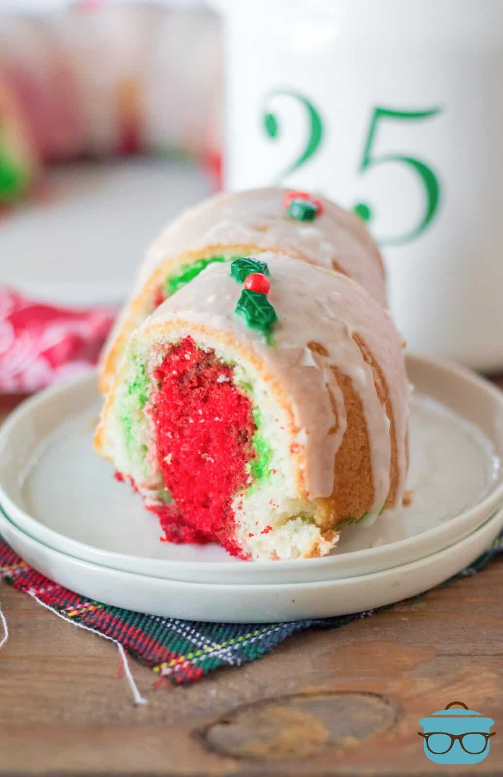 two slices of Christmas bundt cake shown on a white plate so you can see the colorful  red and green inside of the cake.