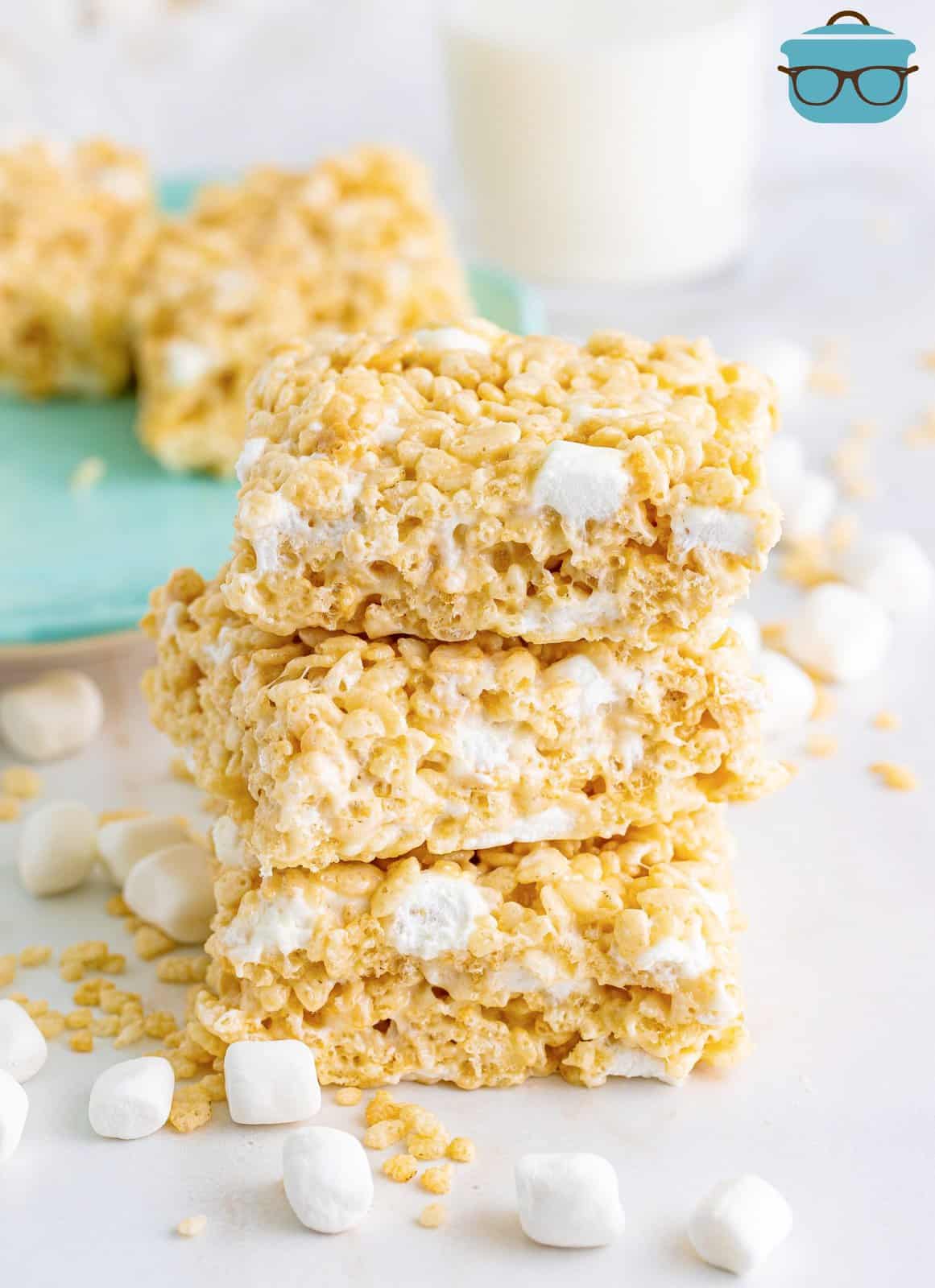 Three Rice Krispie Treats in a small stack with marshmallows around them. 