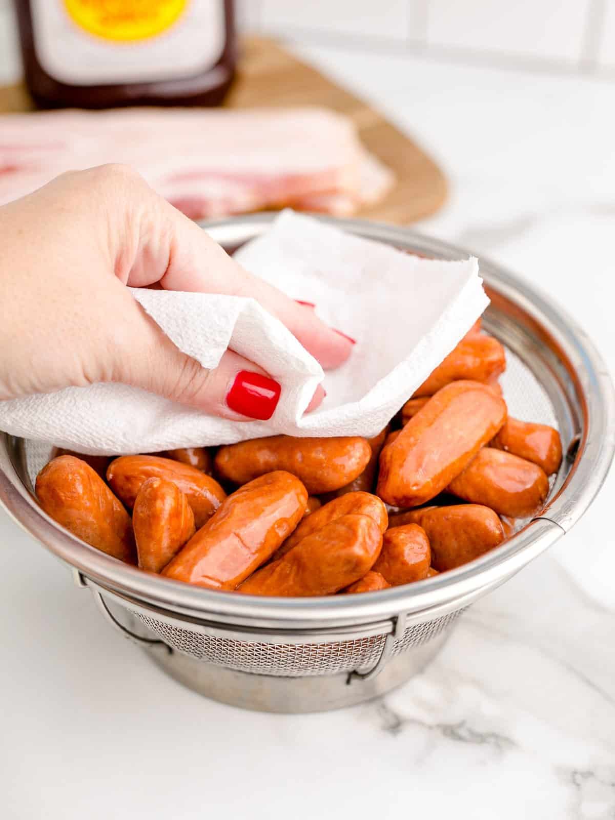 patting cocktail sausages dry with a paper towel.