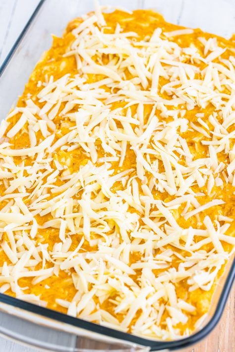 Shredded cheese on top of the enchilada bake in a baking dish.
