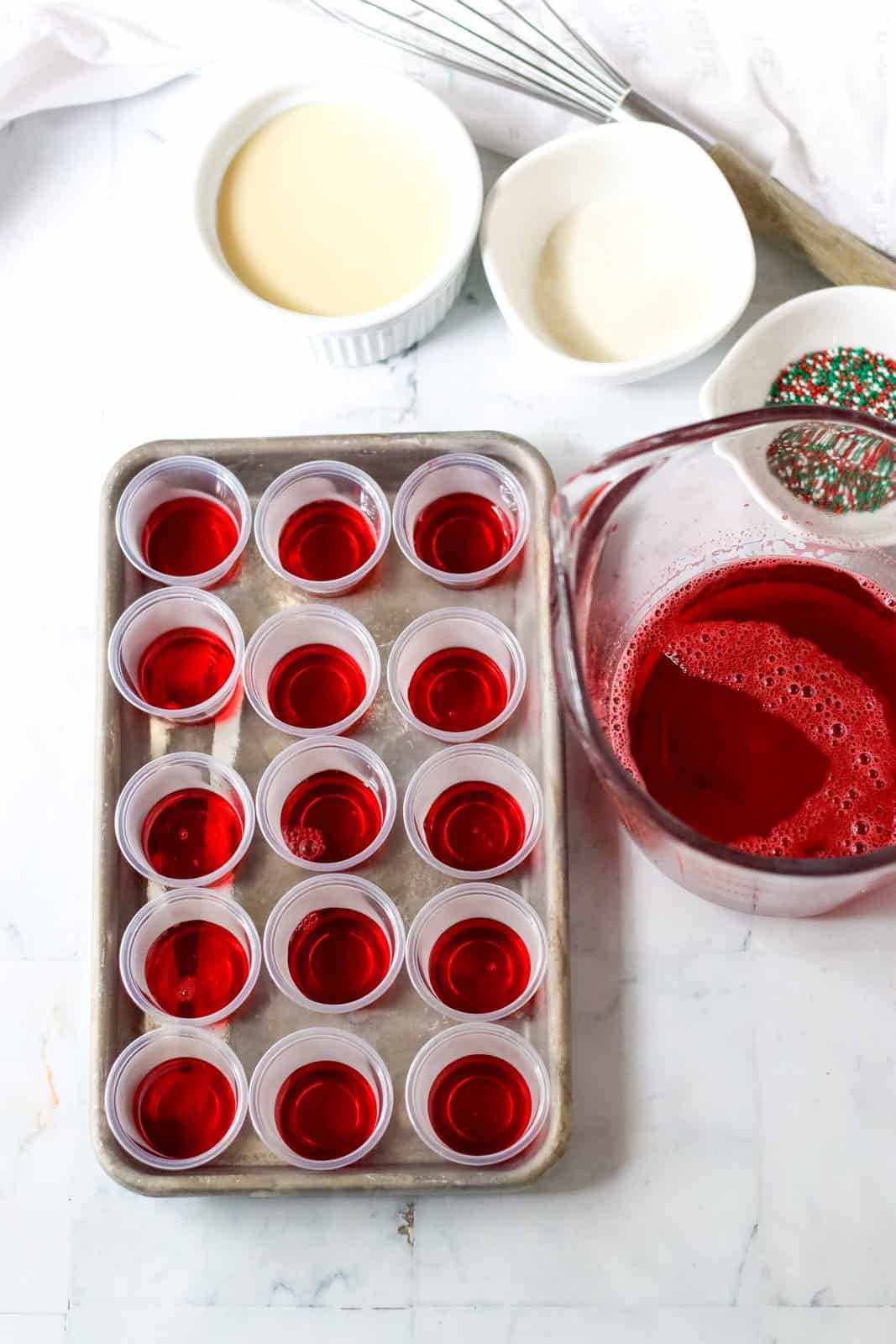 Red Jell-O layer mixed together and poured into cups on tray.